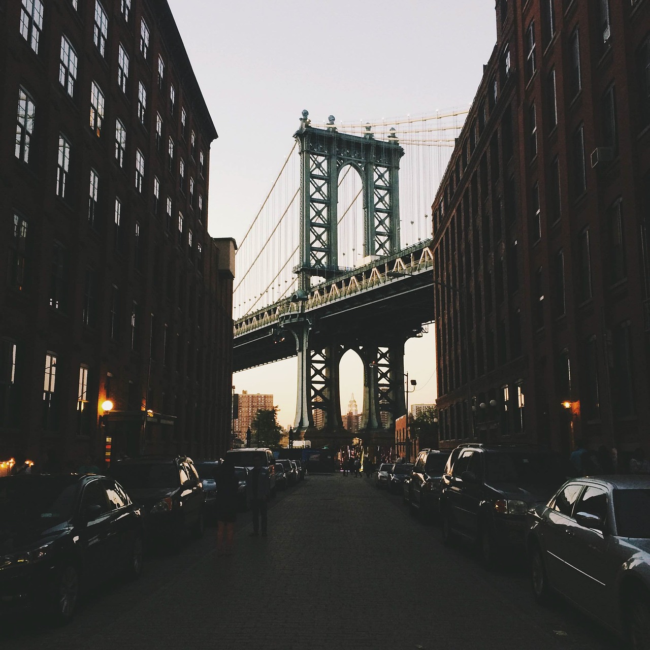 Historic New York brownstone street framing the Manhattan Bridge at dusk